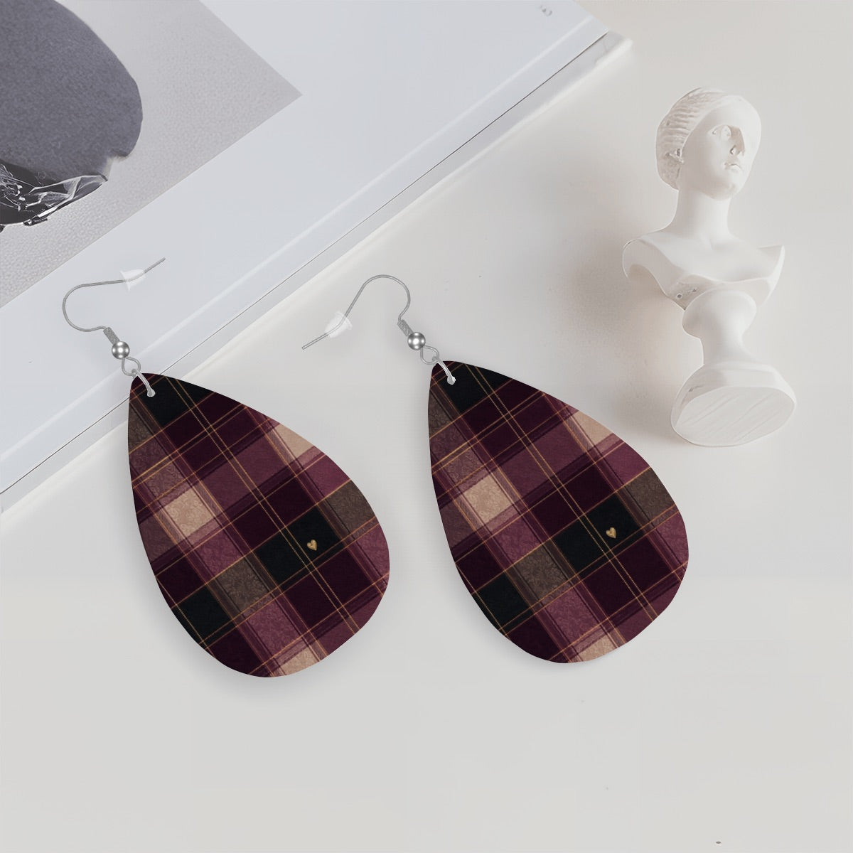 Falling for You plaid heart earrings styled on a white surface beside a small decorative bust.
