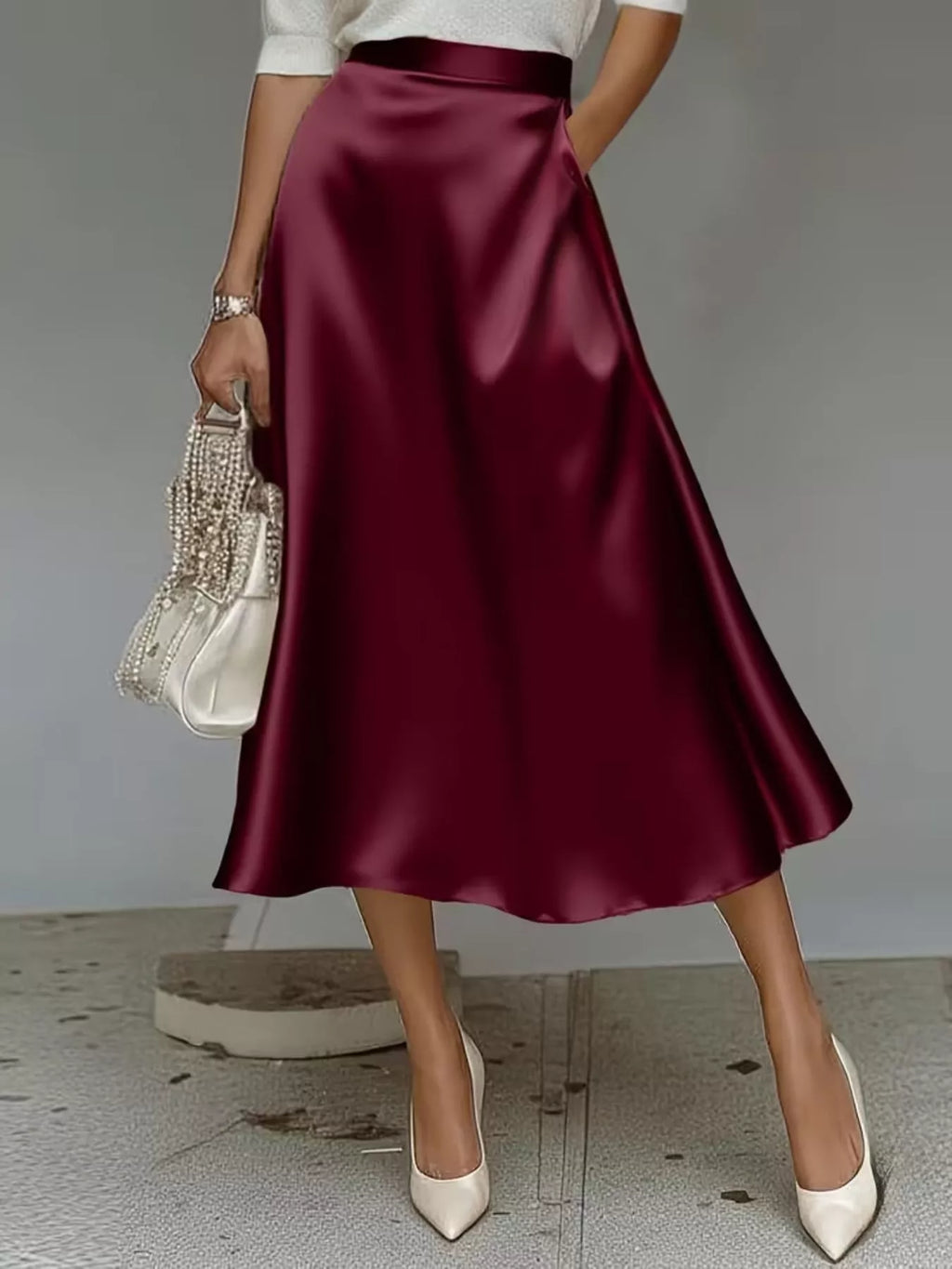 Wine-red soft-sheen midi skirt styled with ivory heels