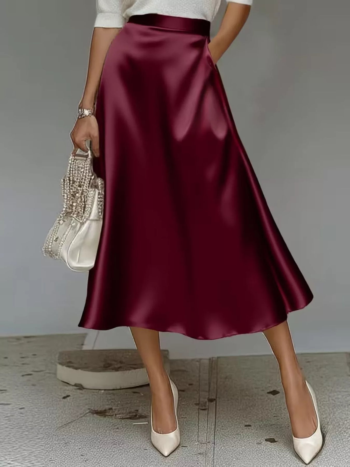 Wine-red soft-sheen midi skirt styled with ivory heels