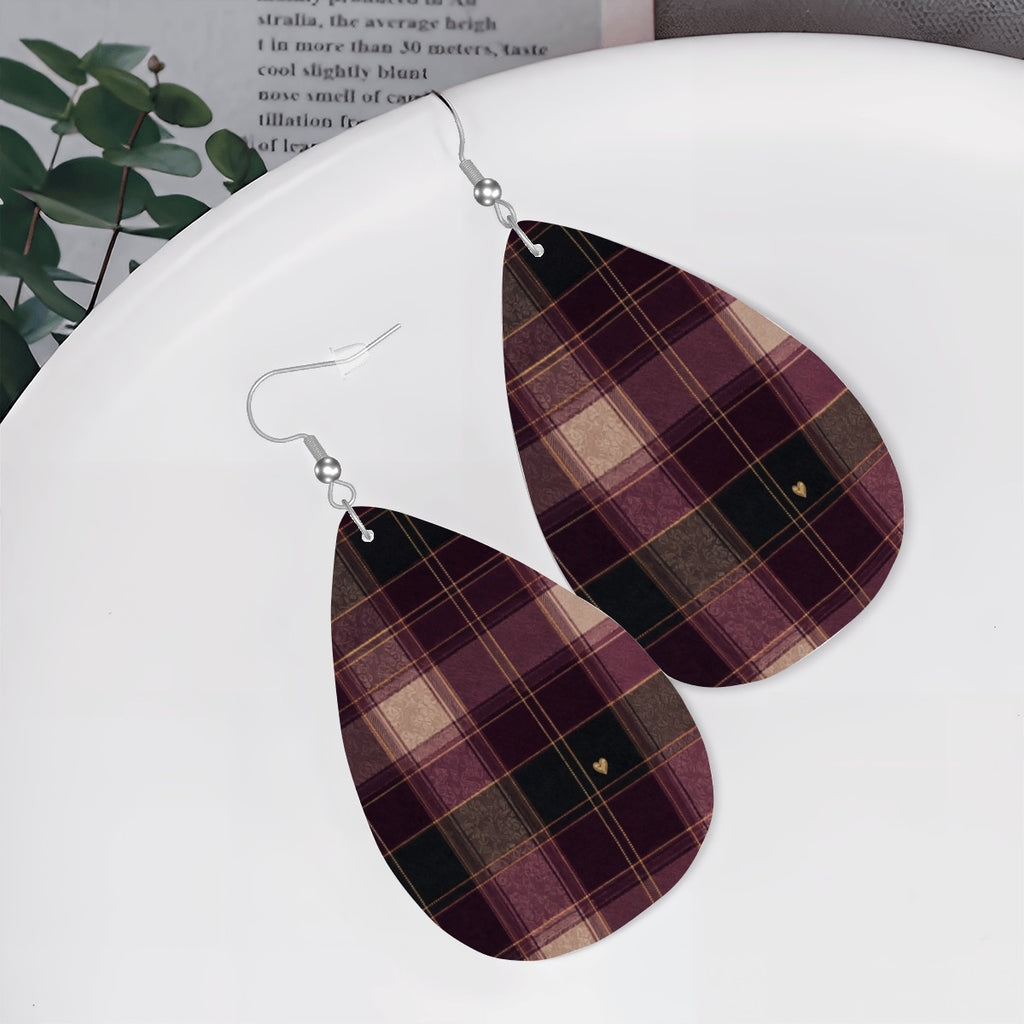 Berry and charcoal-green plaid teardrop earrings displayed on a white dish beside greenery.