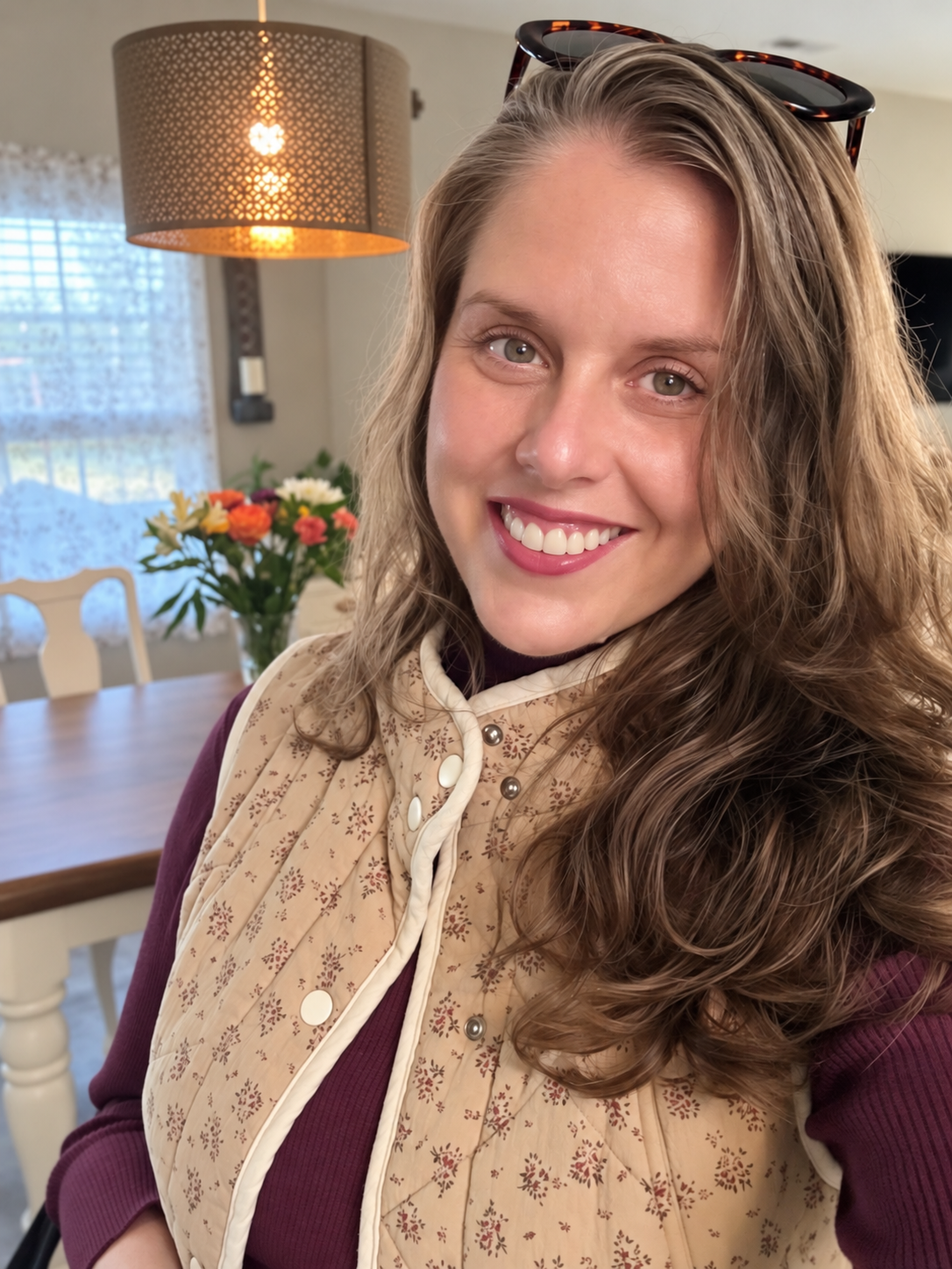 Close-up of Jenny wearing the Meadow Bloom Quilted Cotton Vest, showing the floral print, quilting, cream trim and snap fasteners.